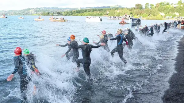 Triathletes charge into the water, kicking up spray as they begin the swim portion of a boulder half ironman race.