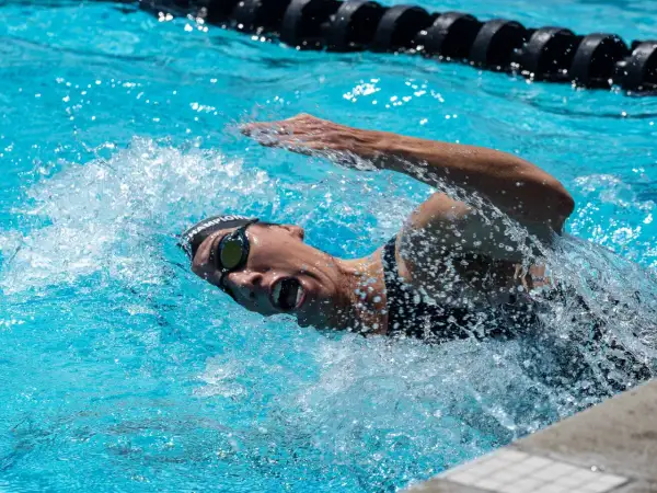 Swimmer in goggles and cap powers through the water, mid-stroke, preparing for a flip turn.