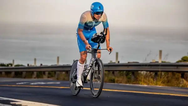 A determined triathlete, perhaps a beginner, races on a bike, focused on the road ahead.