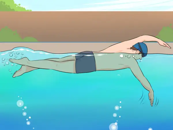 A person in swim cap and goggles practices freestyle swimming, a common stroke for beginner swim lessons for adults.