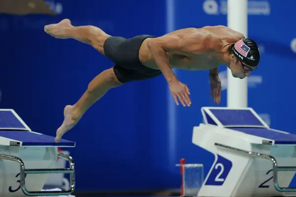 Michael Phelps dives into the water, his body streamlined. His focused expression hints at the intense effort and controlled michael phelps heart rate required for peak performance.