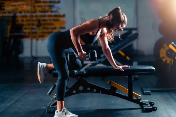 Woman performing a dumbbell row as part of her triathlon strength training plan.