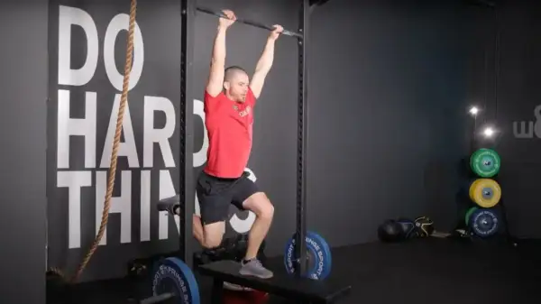 Man performing a hanging exercise, possibly part of butterfly sets, in a gym.