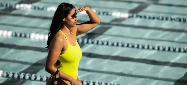 A determined lap swimmer shields her eyes, ready to dive into the pool.