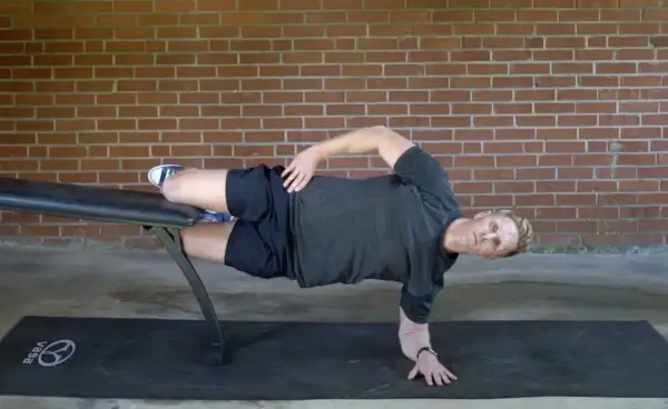 Man performing a side plank on a bench, a key exercise for core workouts for swimmers.