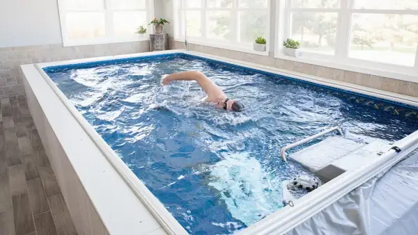 Man swims laps in a compact triathlon pool, enjoying an endless swim against a gentle current.