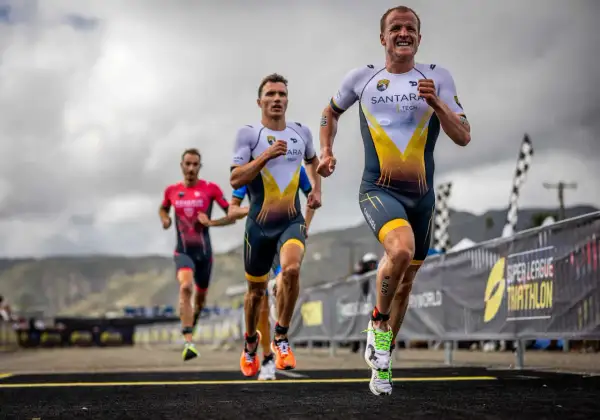 Triathletes race, pushing their limits. The lead runner's determined face hints at the grueling Ironman triathlon distances ahead.