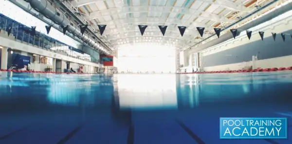 An empty indoor swimming pool with black Speedo flags. While chlorine kills many germs, does chlorine kill COVID?