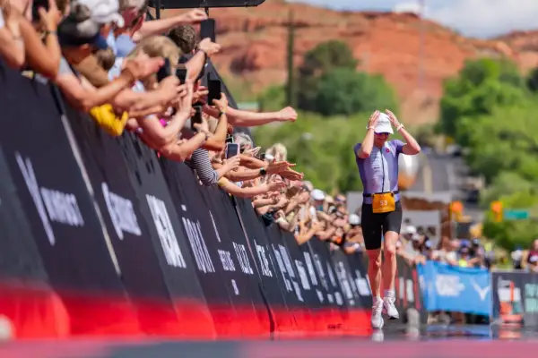 Athlete 53 runs towards the finish line at Ironman 70.3 St. George, greeted by a cheering crowd.