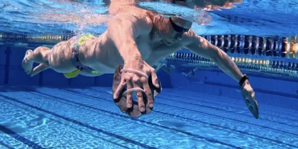 Swimmer performing a paddle drill, using hand paddles to increase resistance and build strength in the water.