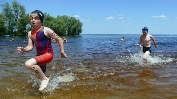 Young athletes splash through the water during a youth triathlon.