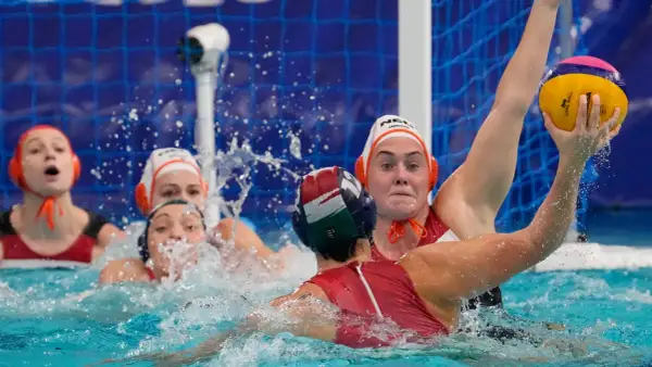 Intense water polo action, with players battling for the ball. The struggle suggests potential water polo fouls as they jostle for position near the goal.