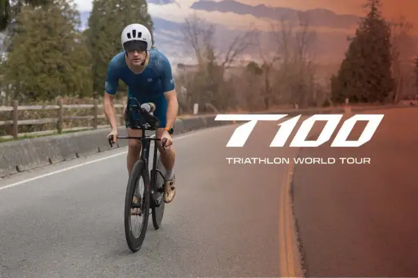 A determined athlete cycles on a road, preparing for the T100 Triathlon World Tour.