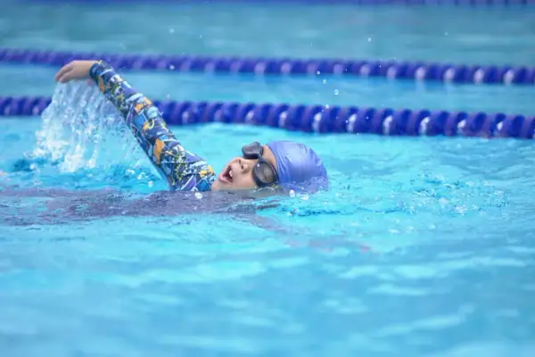 A young swimmer practices the side stroke, their arm slicing through the water.