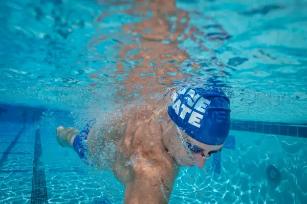 Underwater view of a swimmer's powerful swimmer lats as they glide through the blue water, bubbles trailing behind.
